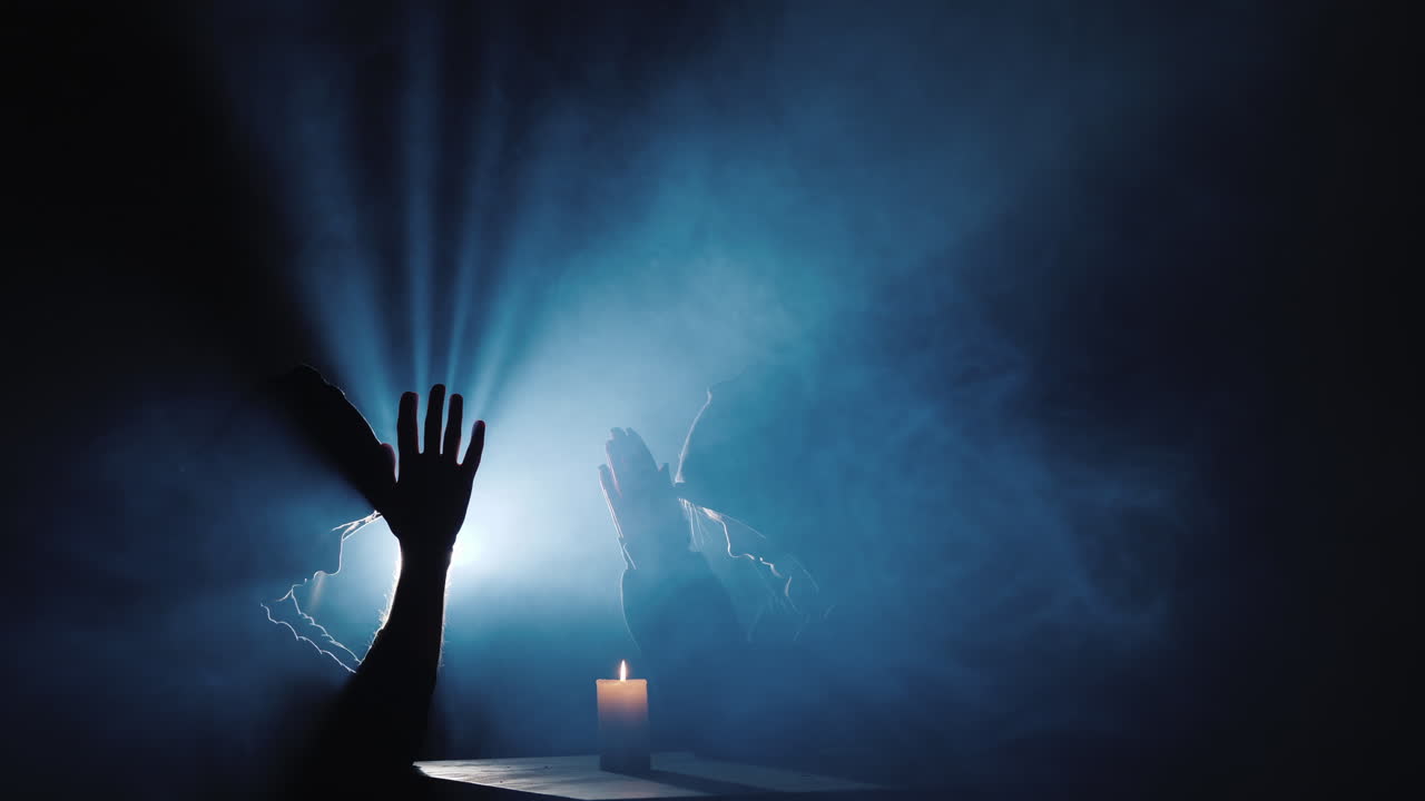 dos hombres encapuchados rezan en la oscuridad en los rayos de luz