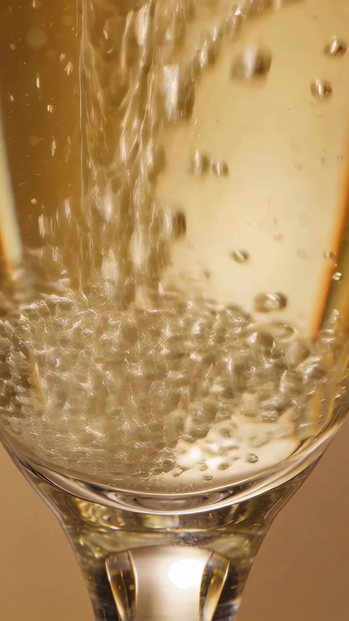 Calice a flûte che si riempie da un getto dall'alto, formando bollicine che salgono e schiuma per il marketing di bevande