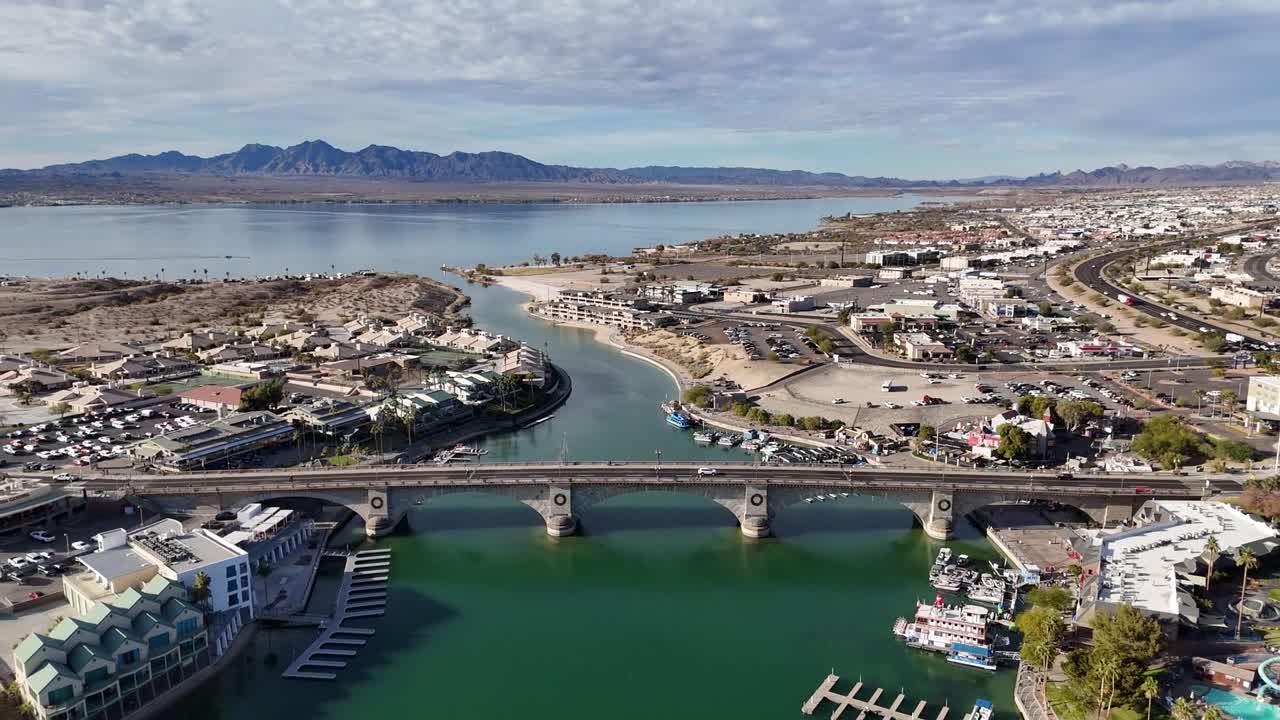 London Bridge in Lake Havasu City Arizona. Drone slowly pulling away and ascending as cars drive across bridge revealing boats, marinas, resorts and mountains