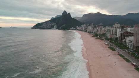 Flyover-establishing-over-the-beach-of-Leblon-Rio-de-Janeiro-Brazil,-Morro-Dois-Irmãos-in-the-background