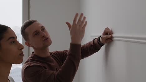couple installing wall molding in their new apartment