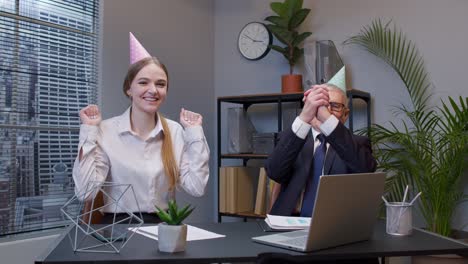 two joyful collegues in formal suits dancing victory dance, celebrating success of business project