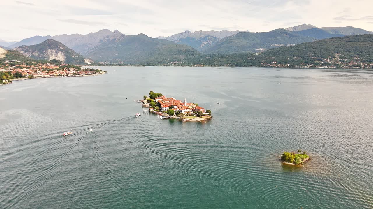 Drone shot pulls back to reveal the full expanse of Isola Bella, showcasing its Palazzo Borromeo and terraced Baroque gardens as it sits within Lake Maggiore, Stresa, Italy, with the Alps background