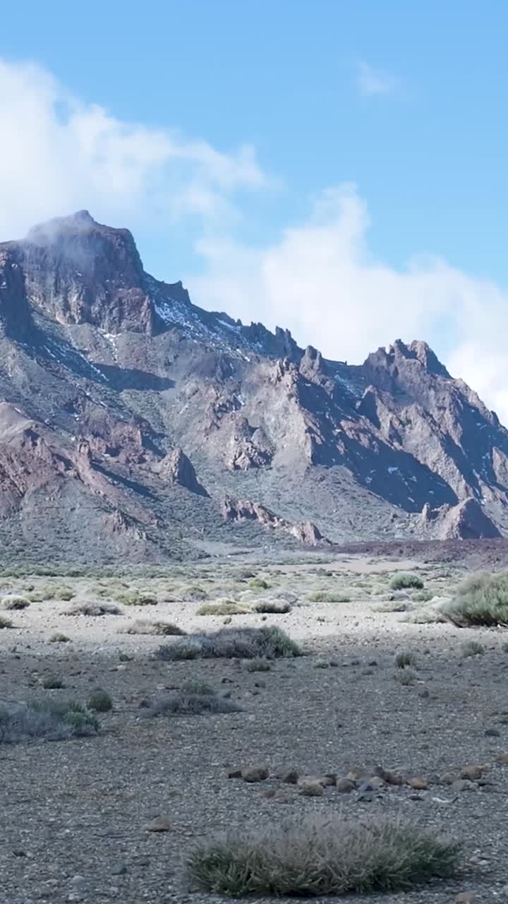 Paesaggio montano arido con nuvole e vegetazione rada