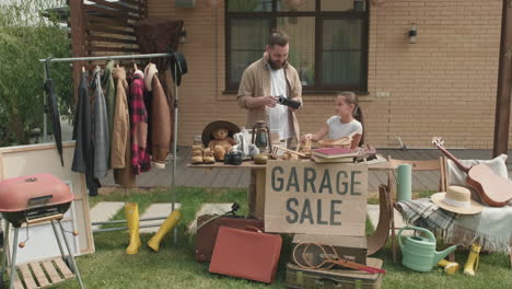 father and daughter having garage sale in summer