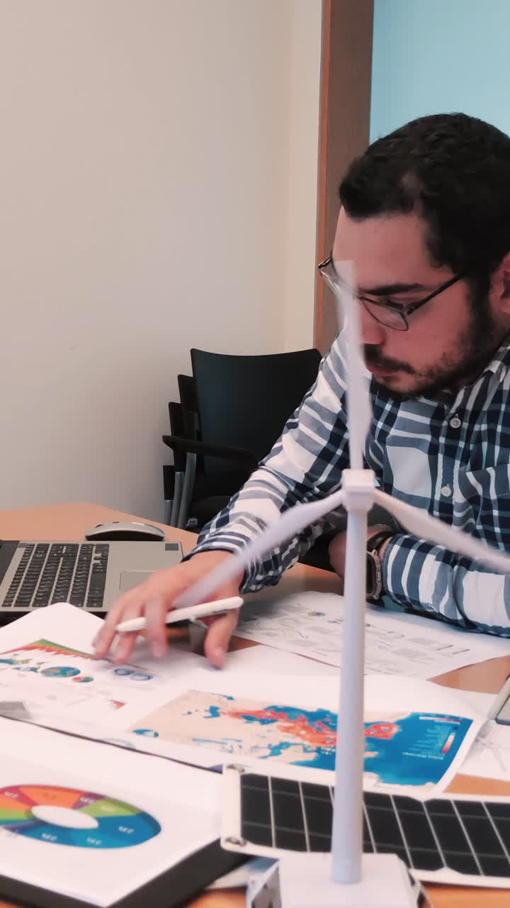 Project Manager Pointing at a Chart, Wind Turbine in Foreground