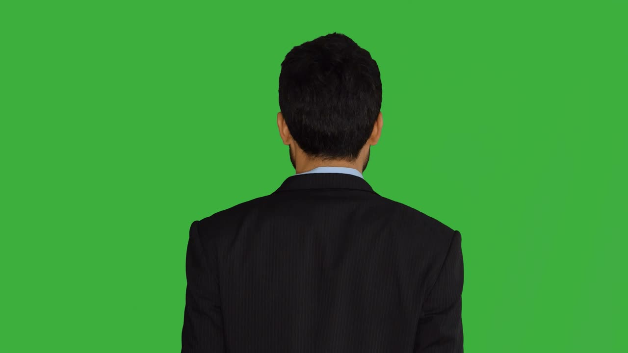 녹색 스크린 앞에 서 있는 젊은 아시아 사업가, 이야기하고, 돌아서며, 웃으며, 성장, 금융, 은행, 은행가, 성공을 상징한다.