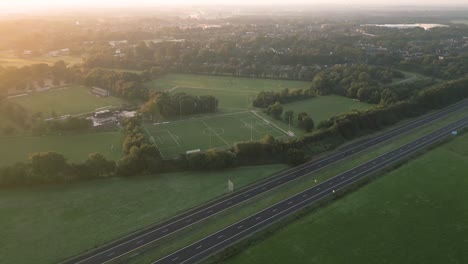 sunrise over a dutch town with highway and sports fields