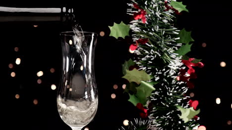 pouring champagne at slow motion in flute with christmas garland decoration and lights