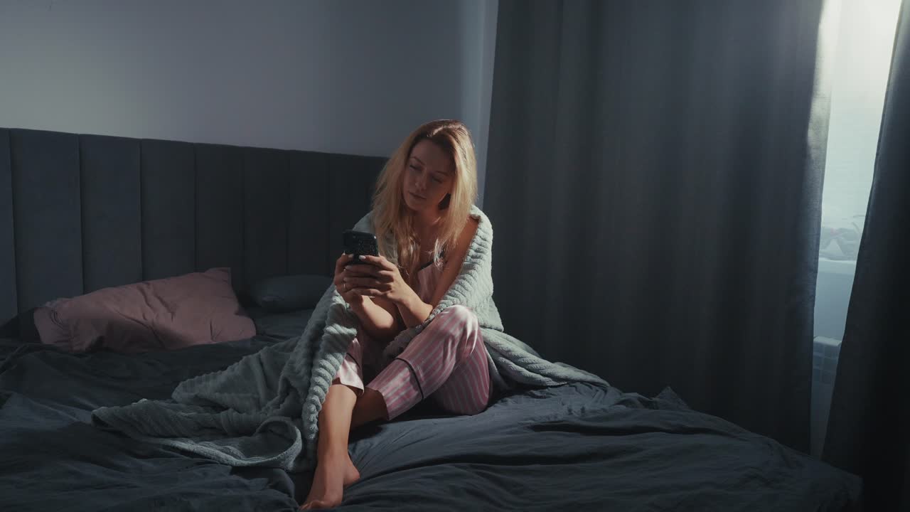침대에서 전화를 사용하는 여자