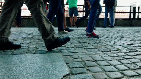 people walk on a crowded sidewalk, close up view of the sidewalk and legs to knee height, slow motion on shoes and footsteps