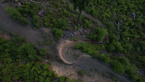 Mountain bikers riding in a train, around a berm in forest area with mountains