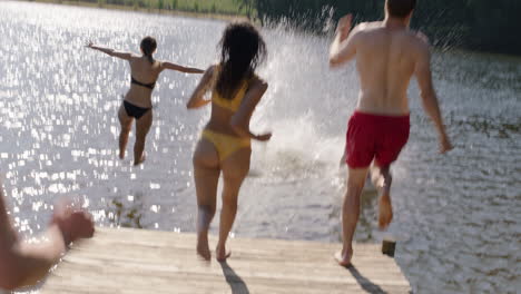 group of friends jumping in lake splashing in water having fun enjoying summer vacation