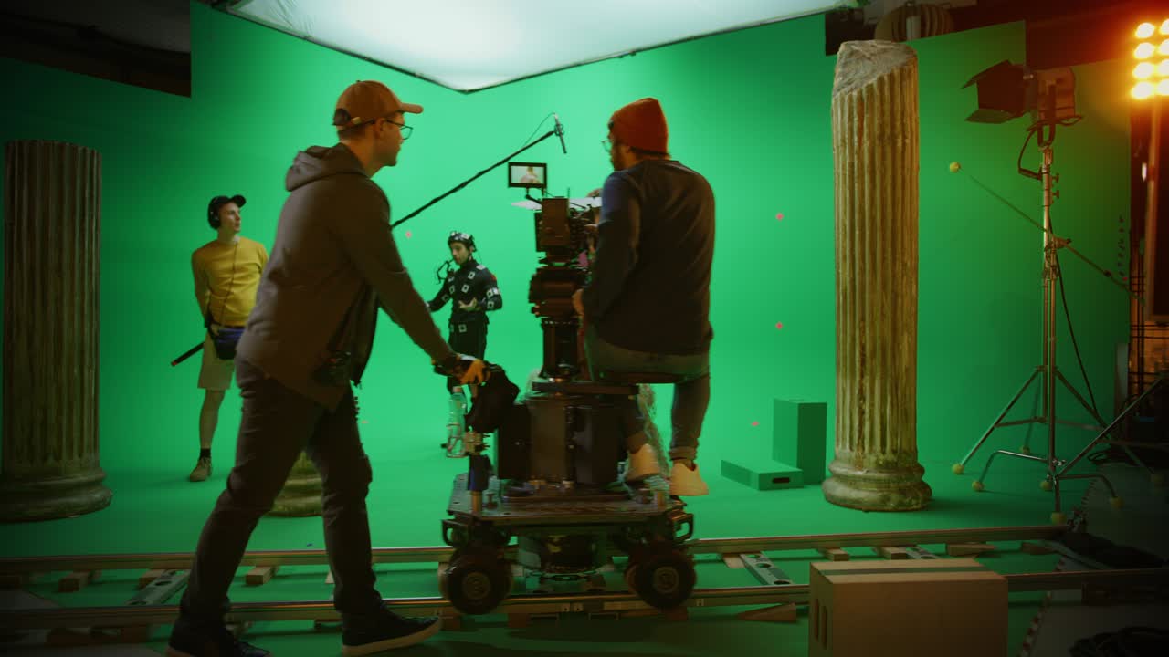 en el estudio de cine, el rodaje de la escena de la pantalla verde de la película de historia. el camarógrafo en movimiento en el tranvía del ferrocarril filma a dos actores disfrazados mientras el director controla el proceso. el equipo profesional en la realización de películas de presupuesto