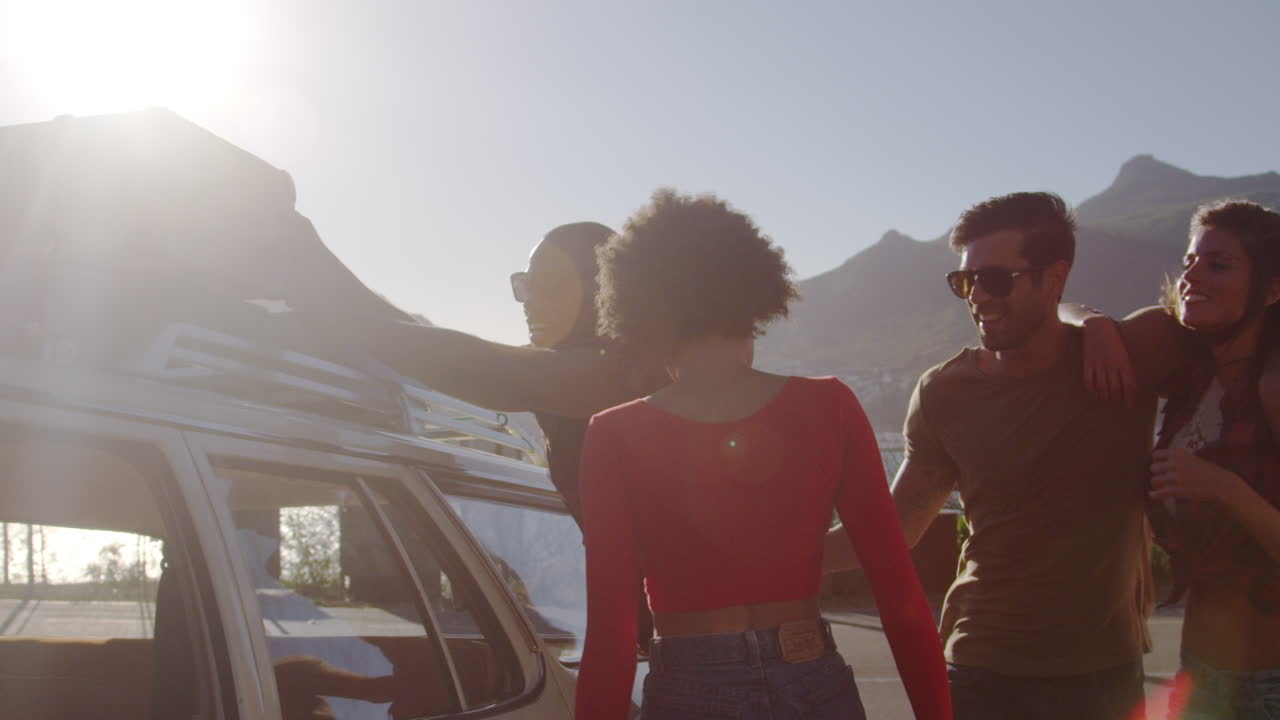 Friends Loading Luggage Onto Car Roof Rack Ready For Road Trip