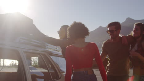 friends loading luggage onto car roof rack ready for road trip