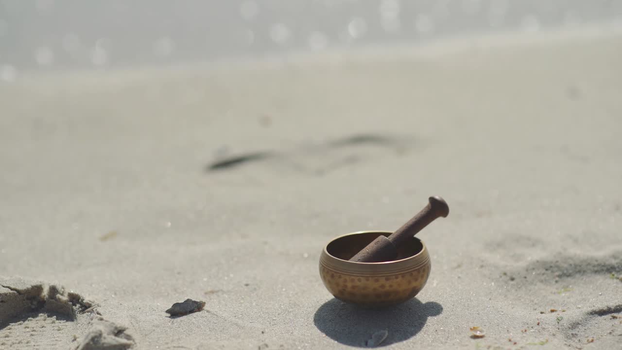 cuenco de canto tibetano de bronce para la meditación en la playa de mar de arena