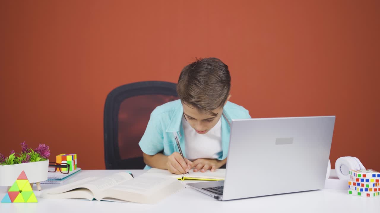 un chico concentrado trabajando en una computadora portátil.