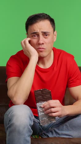 sad man eating chocolate watching movie on green screen