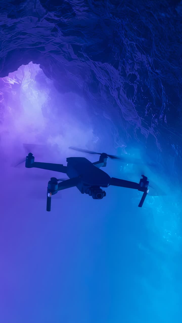 Vertical video: Spinning rotors starting drone keeping hover at cavern wall filming colored glow