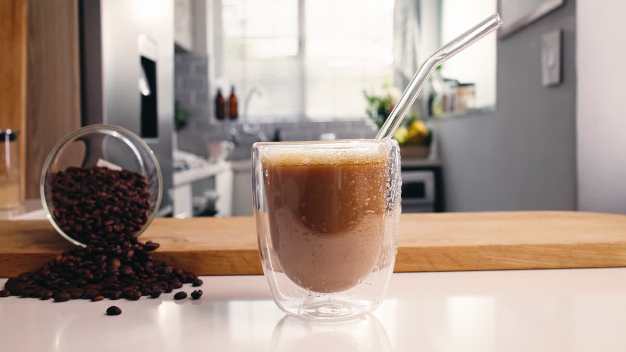Versare latte in caffè freddo con chicchi di caffè sul bancone della cucina