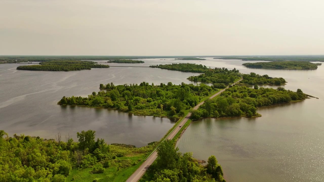 Riprese aeree con drone della Long Sault Parkway che attraversa il fiume San Lorenzo in Ontario, Canada, collegando isole panoramiche con ampie vedute sull'acqua e molteplici isole visibili lungo l'orizzonte