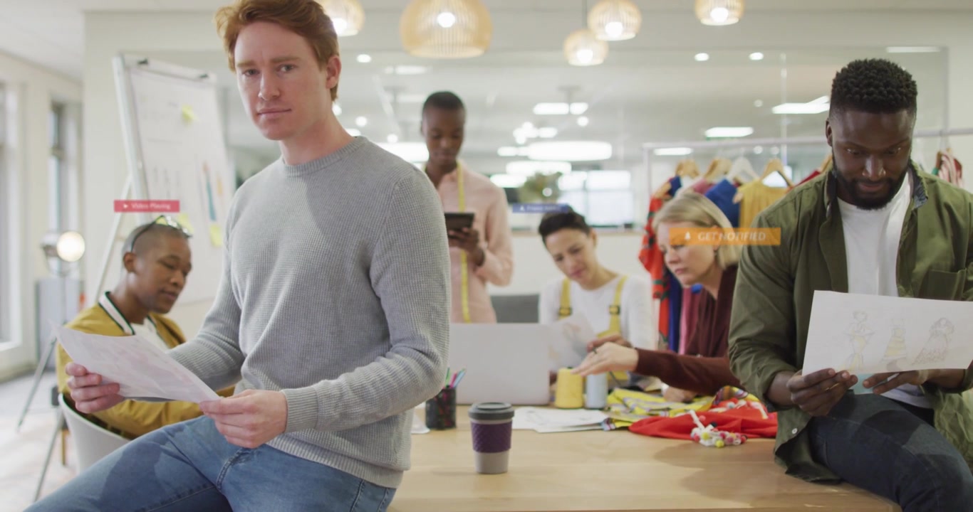 Redhead reading prints glancing up while phone tap making UI overlays over studio for design review