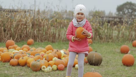 girl posing with bright pumpkin in yard