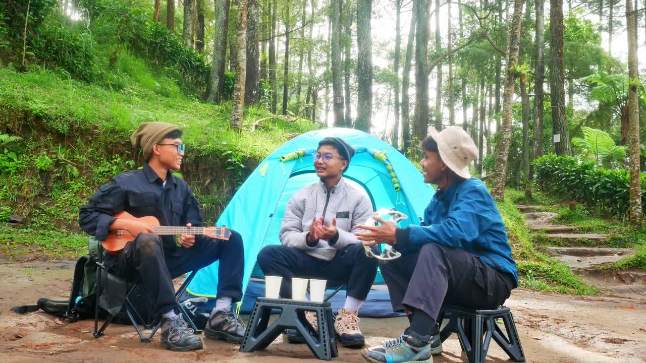 Friends camping and enjoying outdoors with music and laughter in beautiful forest setting