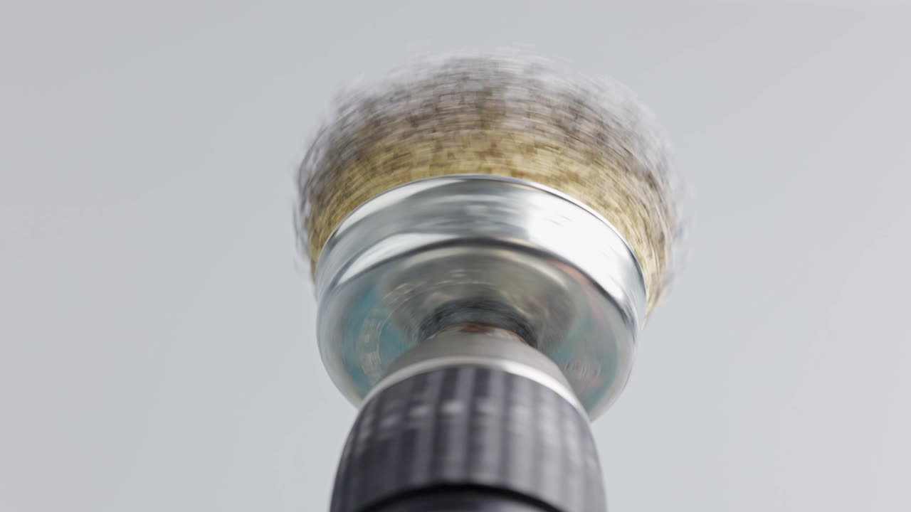 색 배경에 회전하는 둥근 강철 질을 가진 손 드릴