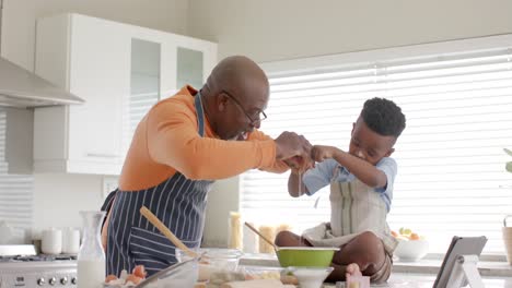 Feliz-Abuelo-Y-Nieto-Afroamericano-Divirtiéndose,-Horneando-En-La-Cocina,-Cámara-Lenta