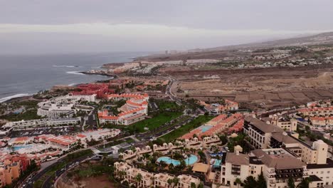 panoramic aerial shows urban development, pools, and coastline at costa adeje