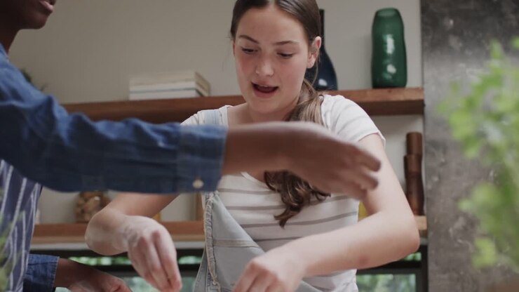 Two happy diverse teenage female friends preparing pizza together in slow motion