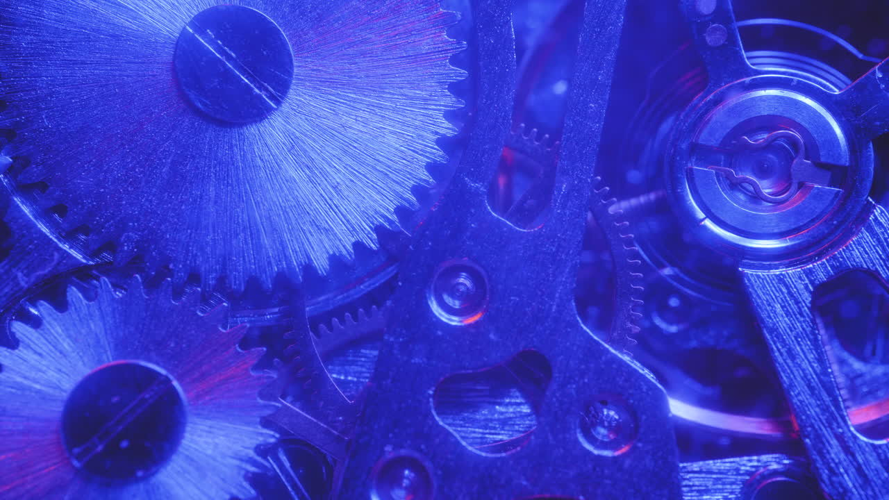Tandwielen op het mechanisme van een horloge onder rood en blauw licht
