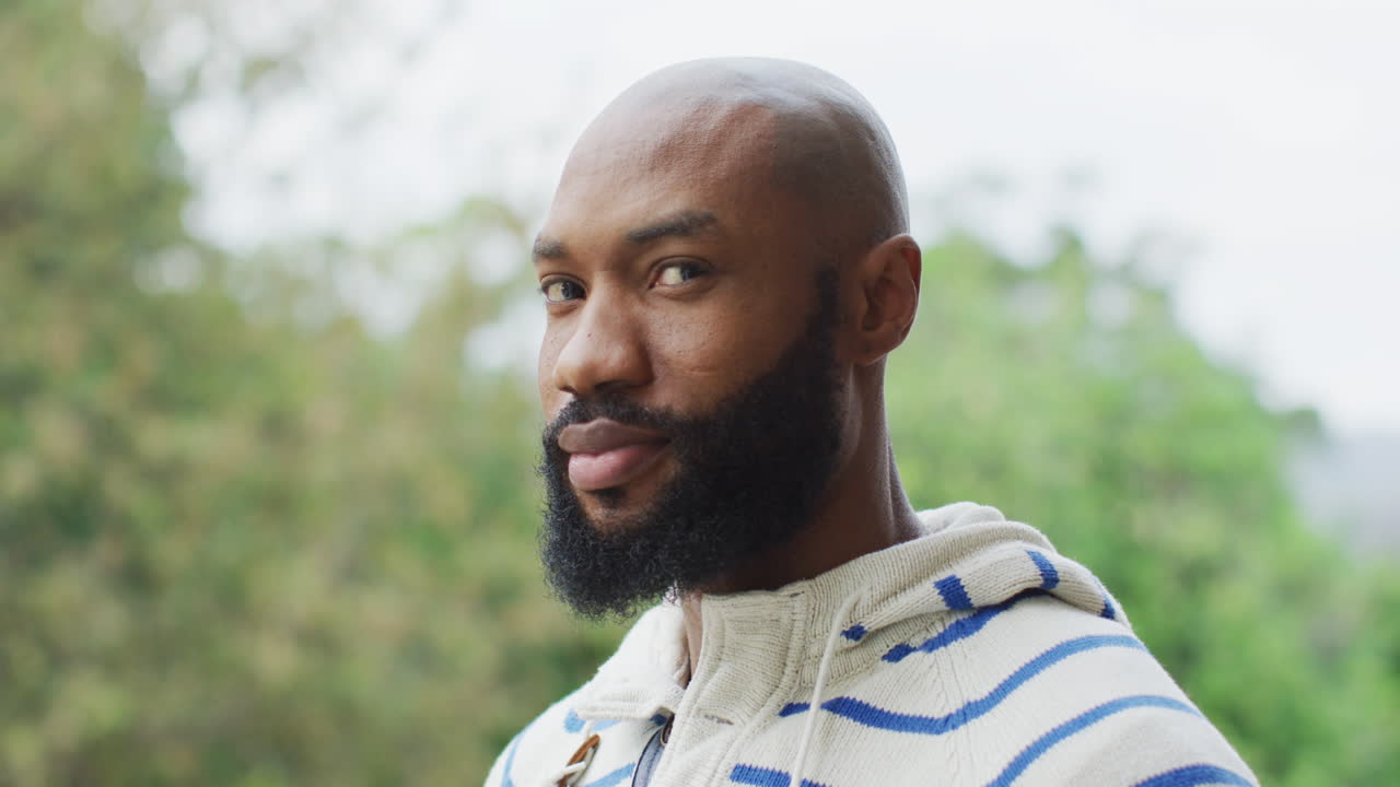 줄무 후디 를 입고 야외 에서 카메라 를 바라보는 수염 을 가진 아프리카계 미국인 남자