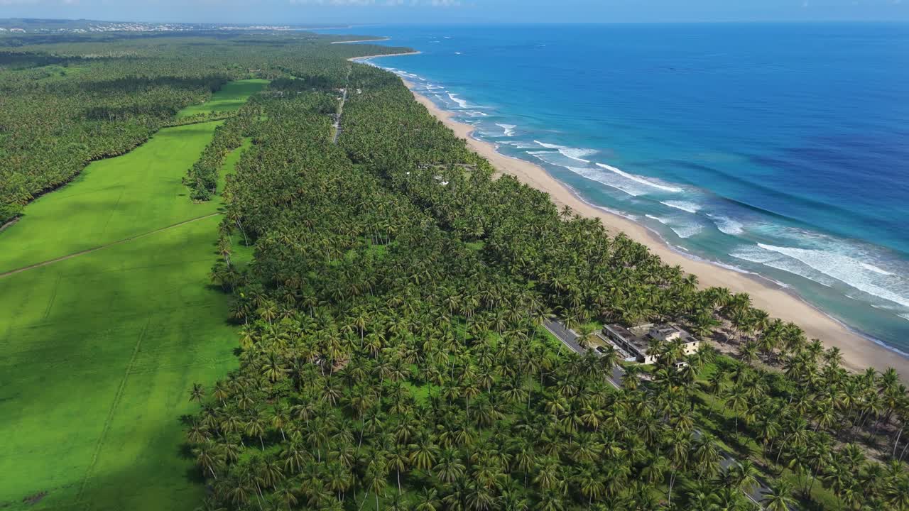Aerial shot of the entrance to Nagua, featuring the lively street scene with the beach and crashing waves on the right, capturing the essence of this beautiful tropical coastal paradise.