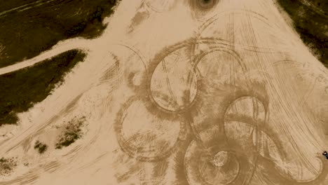 Top-down-aerial-view-of-vehicle-spinout-tracks-in-the-sand-of-Florence,-Oregon-dunes-near-Jessie-M