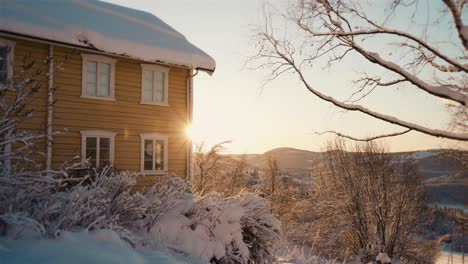 golden sunrise behind yellow house during snowy winter day in norway,europe