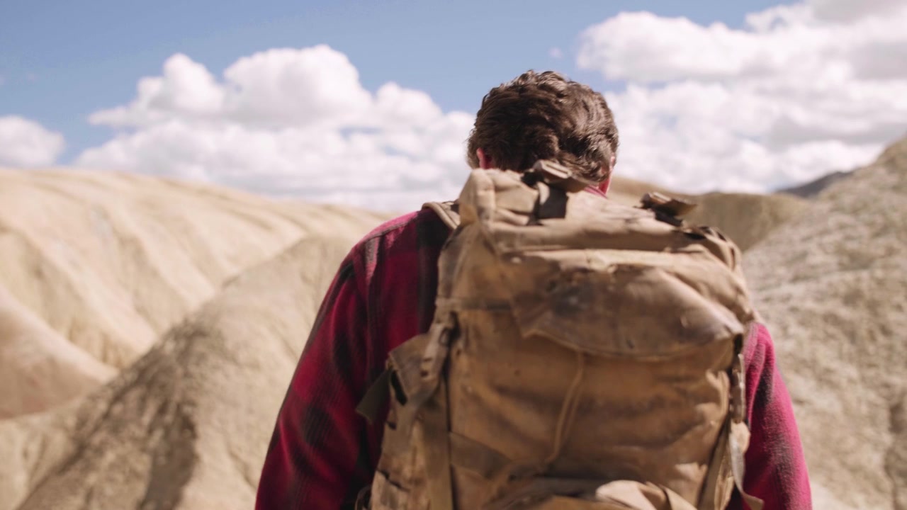 Man with Backpack Walking Through a Dry Desert Landscape