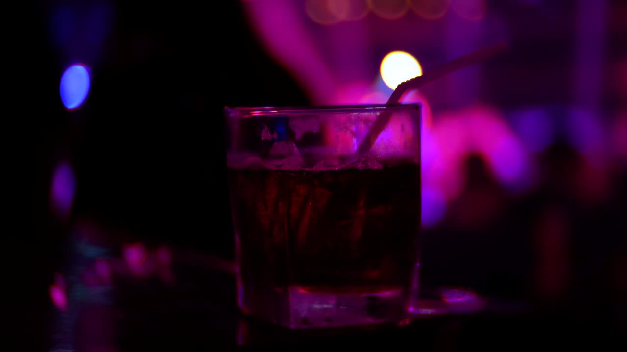 primo piano di un cocktail alcolico in bicchiere sul bancone di un bar, in un nightclub. sfocamento dello sfondo, 4k