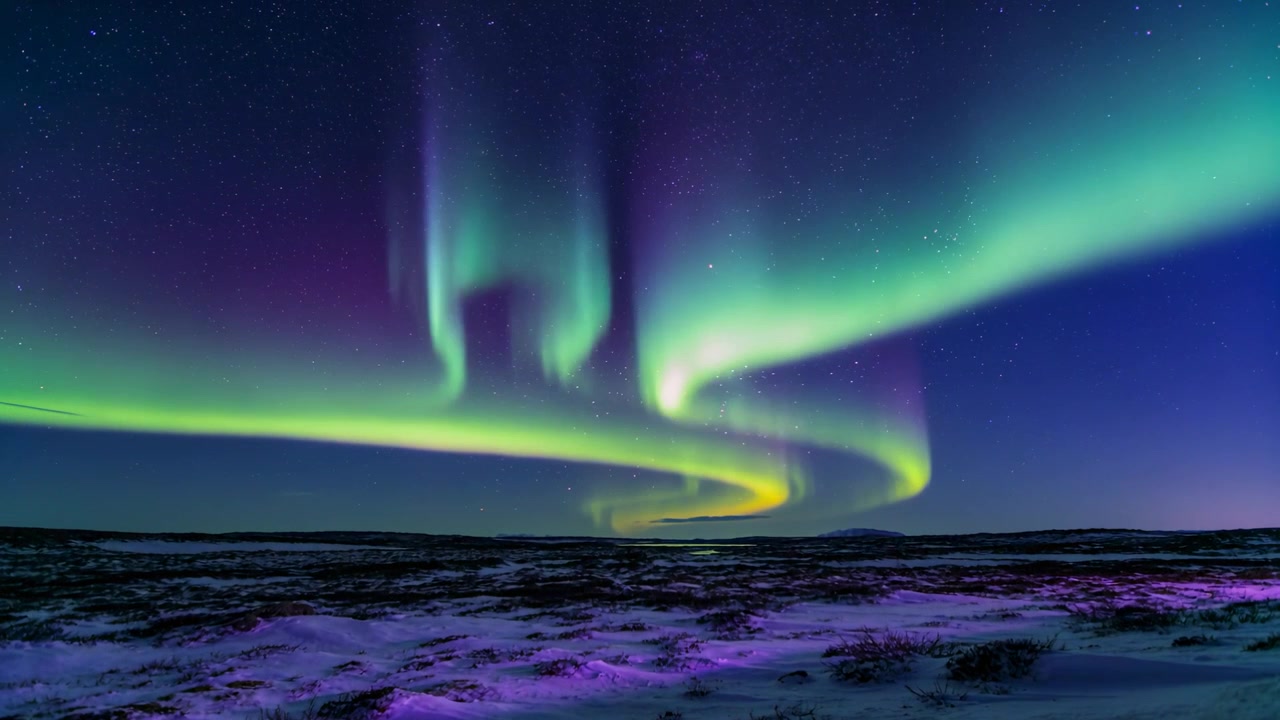 Nastro aurorale che si sposta, si stringe, si illumina e si estende sulla tundra innevata, innescato da una tempesta.