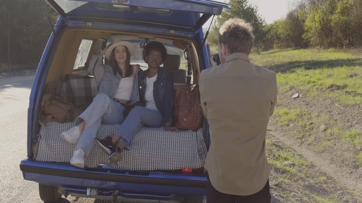 A Young Photographer Taking Pictures Of To Two Beautiful Young Girls Inside A Caravan During A Roadtrip