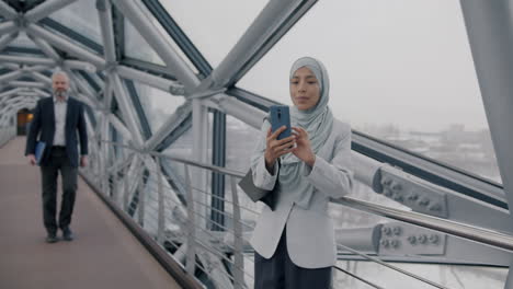 Businesswoman using a smartphone on a city bridge