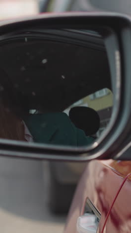 impatient woman looks in car side mirror to check road condition. upset female driver sits in red vehicle waiting out traffic jam closeup slow motion