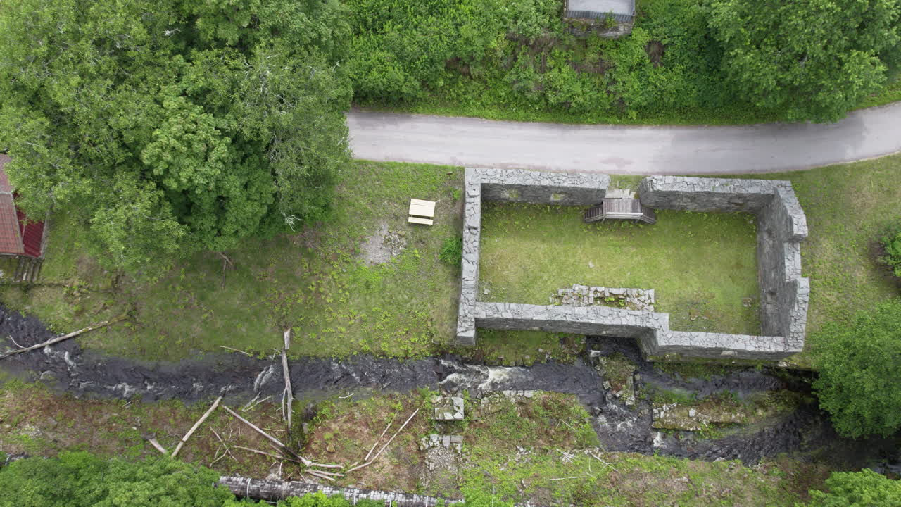 Establishing drone shot of ruins of Backefors Bruk ironwork with river in Bengtsfors Municipality, Sweden