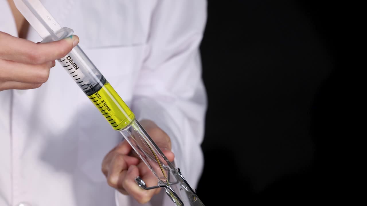 el científico lleva a cabo un experimento con una jeringa y un vaso