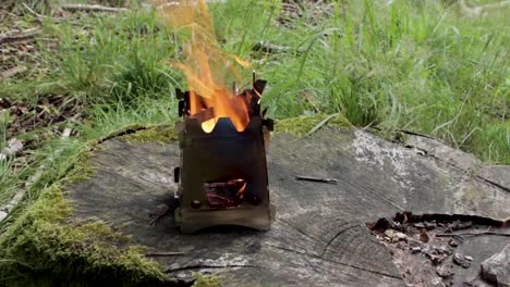 man preparing water for coffee close to a firebox wood stove with orange flames