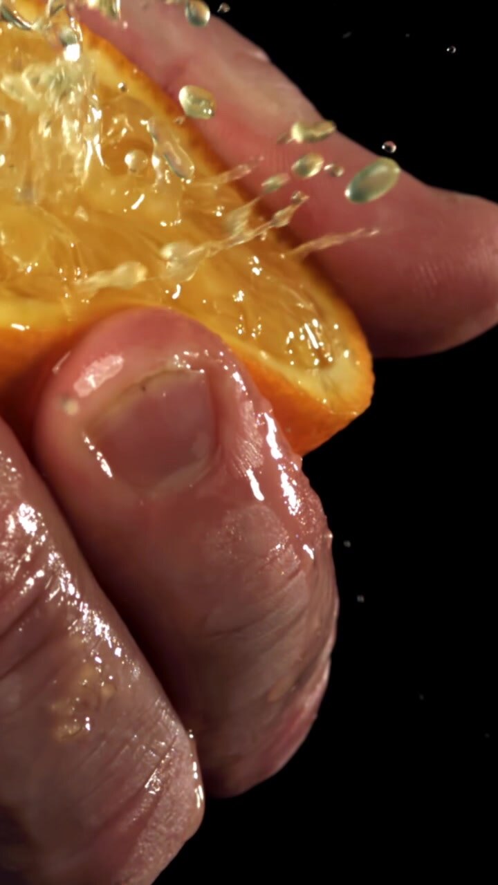 Primo piano al rallentatore di acqua che si versa su una fetta d'arancia