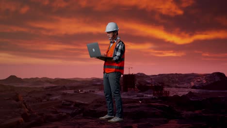 engineer working on laptop at a mining site during sunset