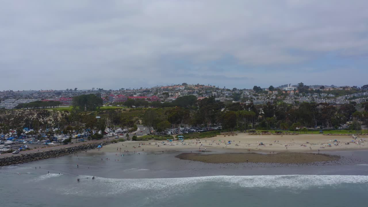 사람들이 목욕하고 휴식을 취하는 해변과 함께 해안을 향해 날아가는 아름다운 공중 드론 샷, 다나 포인트 - 오렌지 카운티 - 캘리포니아